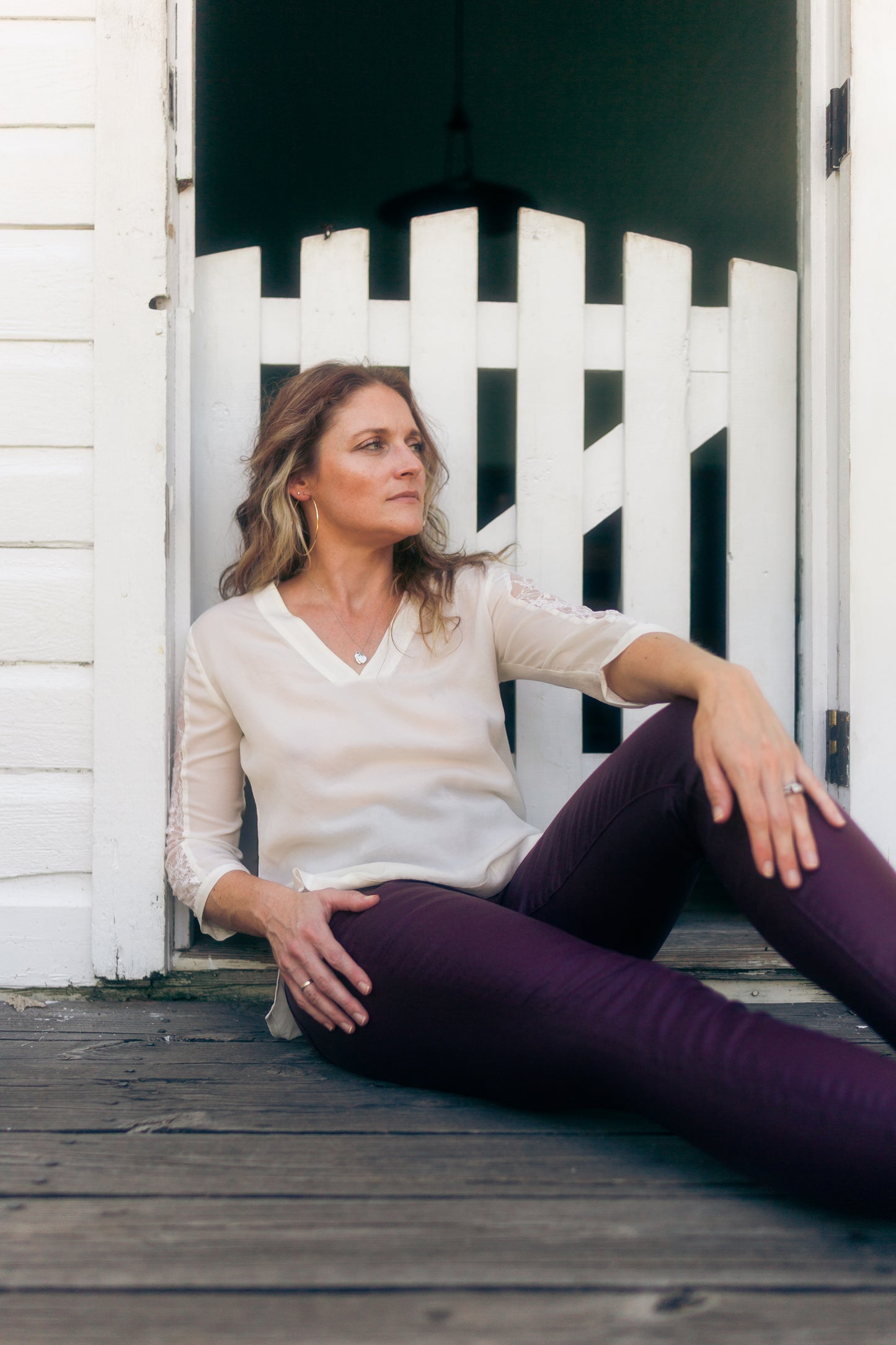 Woman sitting on a wooden deck with a white picket fence in the background