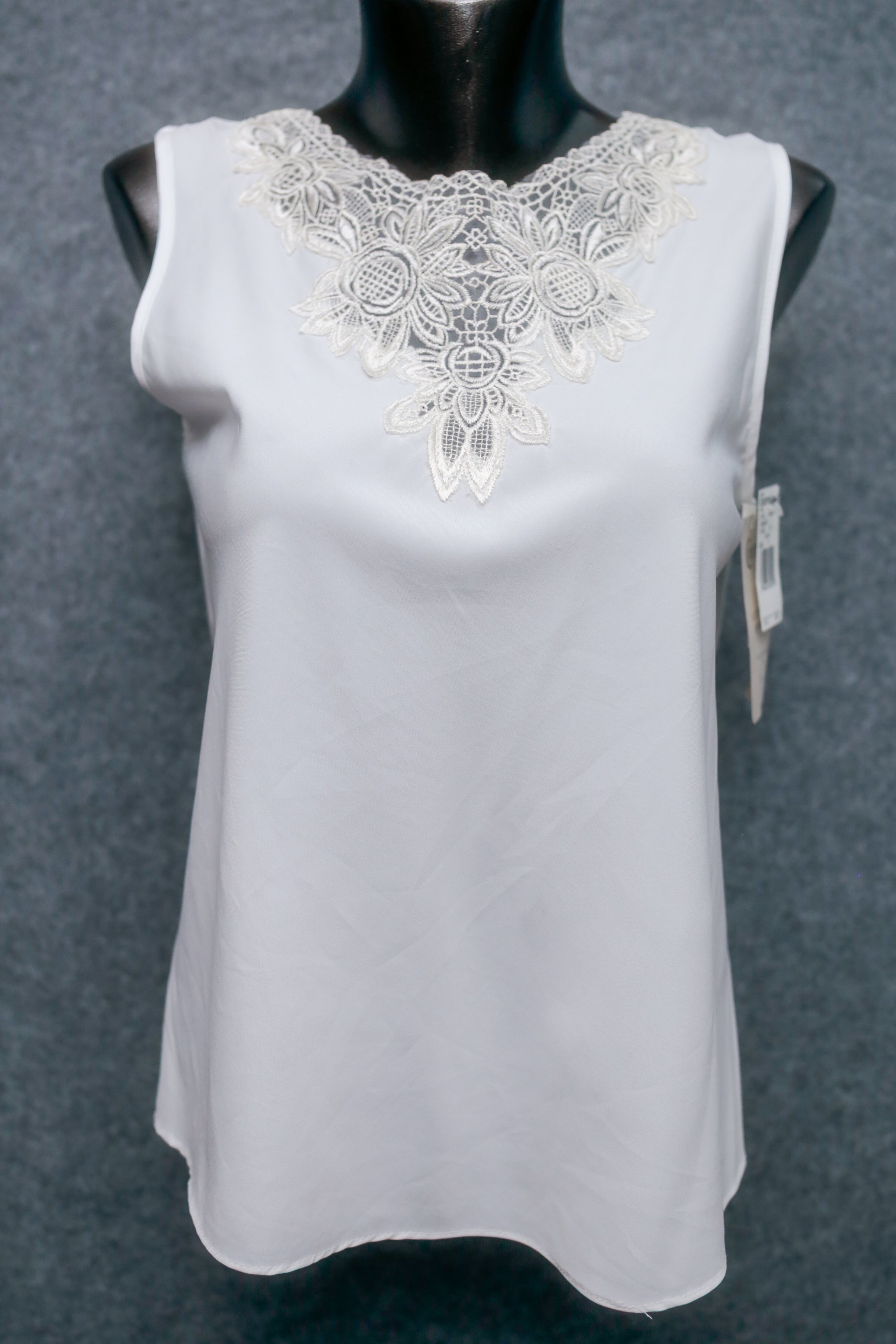 White sleeveless top with lace neckline on a mannequin against a gray background