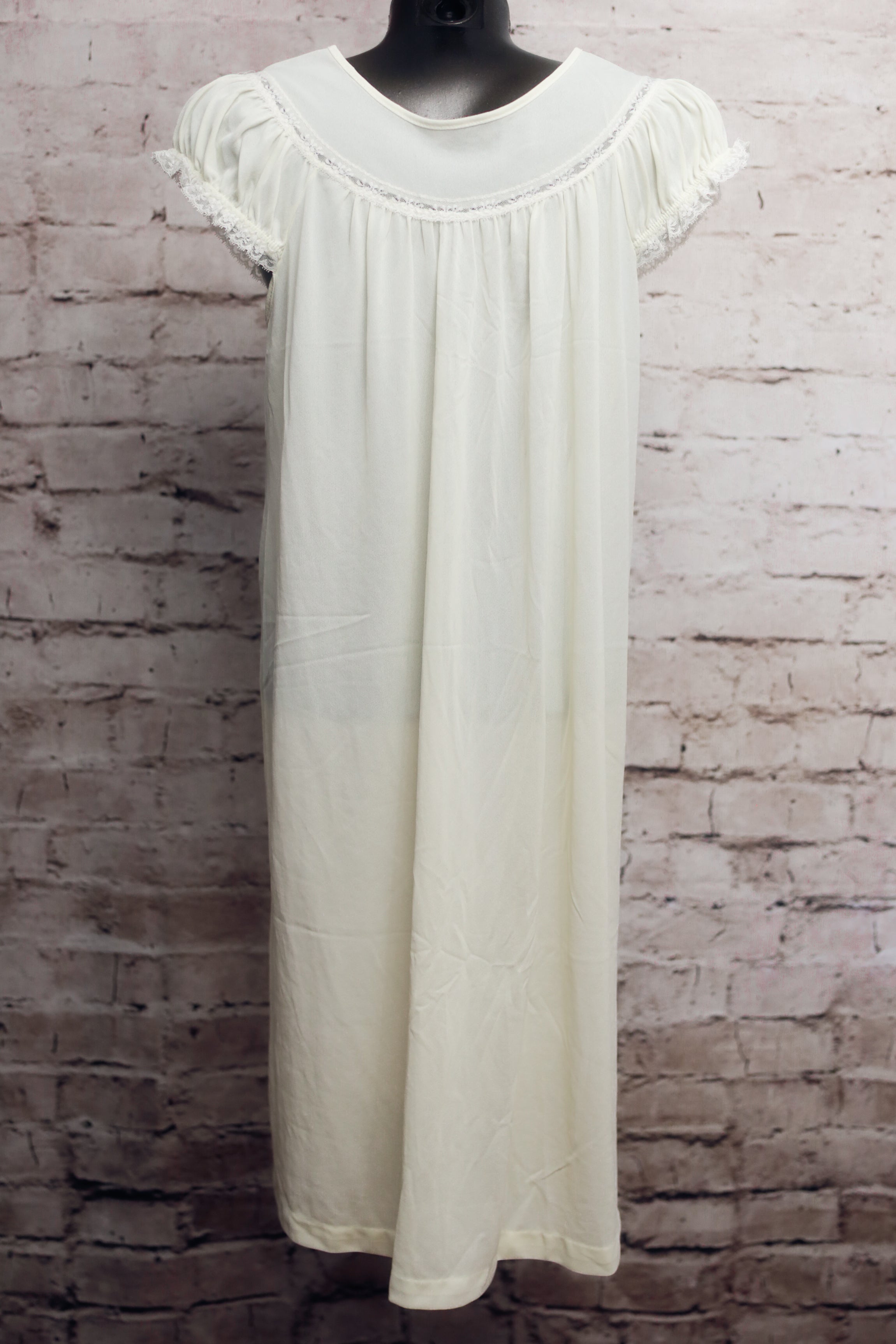 White dress on a mannequin against a brick wall background