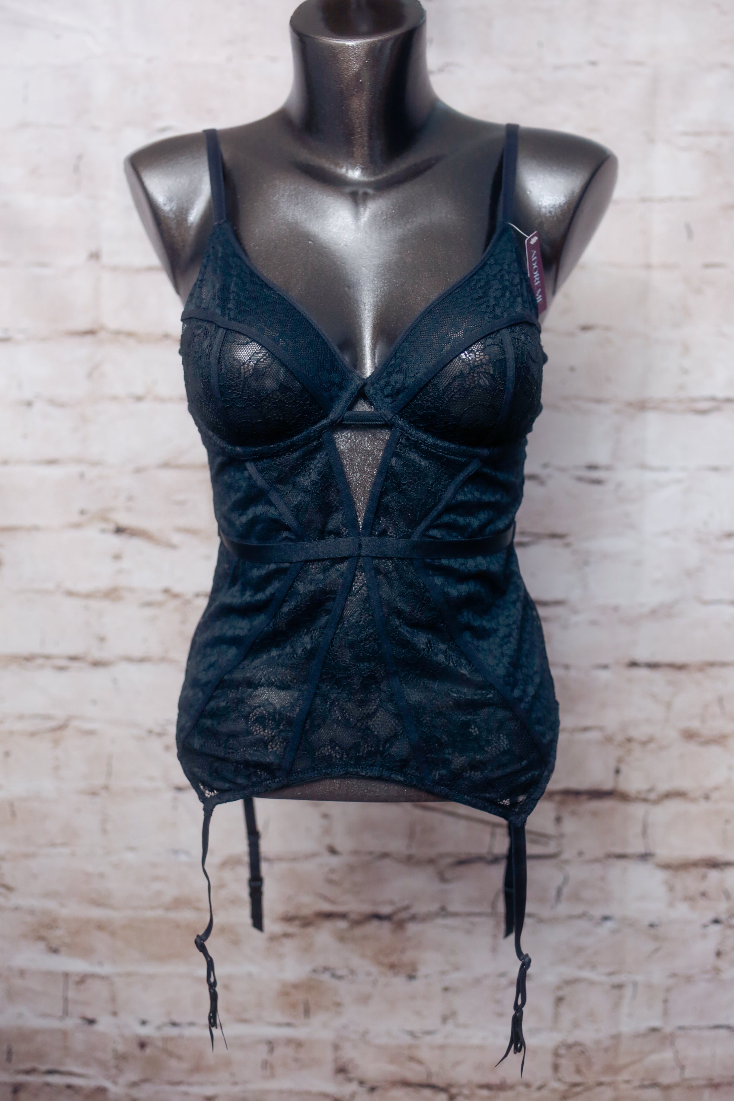 Black lace lingerie set on a mannequin against a textured beige wall